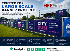 HFE Signs promotional banner showcasing large-scale event branding solutions. The image features branded crowd-control barriers at an outdoor festival venue with the headline "Trusted for Large Scale Banner Projects." Key benefits highlighted include larg