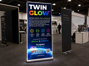 Premium TwinGlow illuminated roller banner in trade show environment, available in 850mm and 1000mm widths